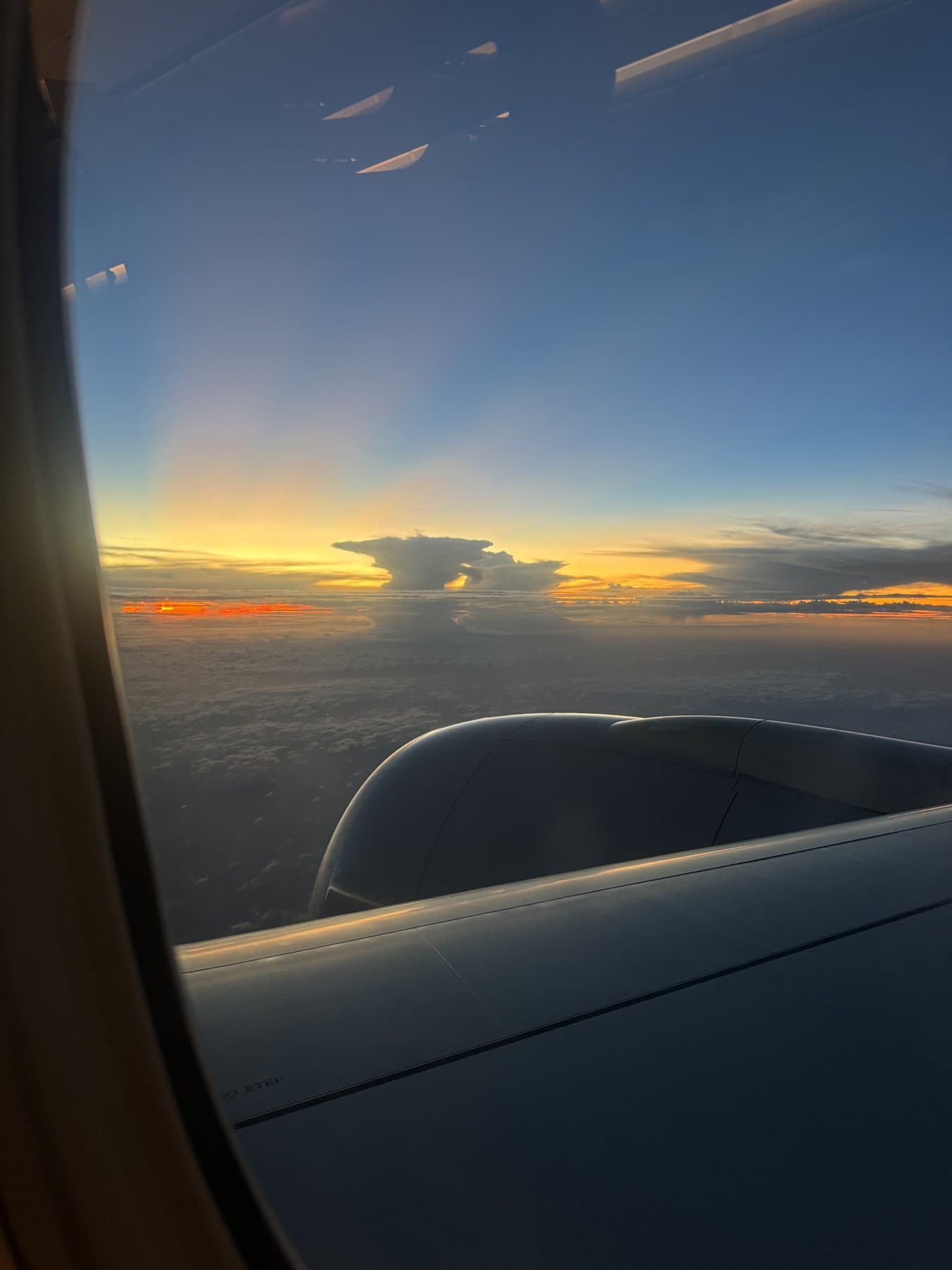 Sunset above the clouds seen past the wing of a Boeing 777