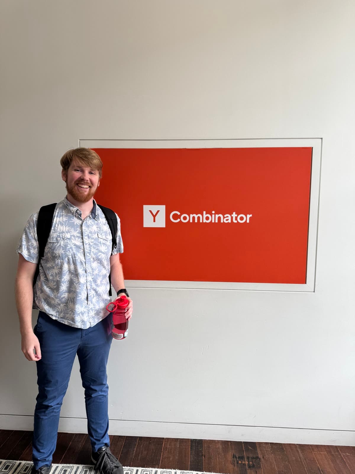 Frank smiling in front of the orange Y Combinator sign